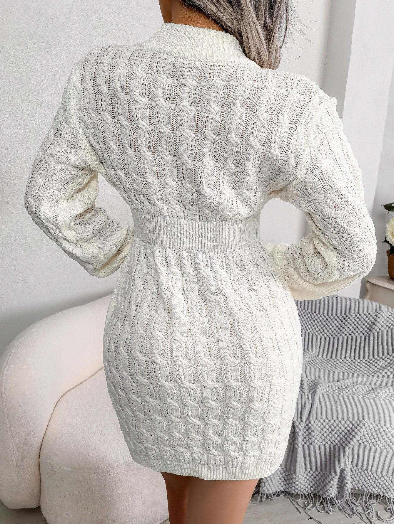 White cable knit sweater dress with a fitted waist, worn for cozy winter outfits.