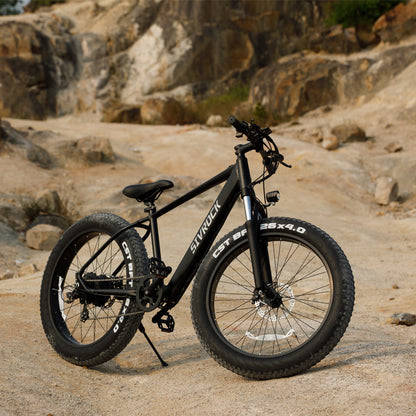 Matte black aluminum all-terrain bike with thick tires on a rocky trail for outdoor mountain sports and recreation.