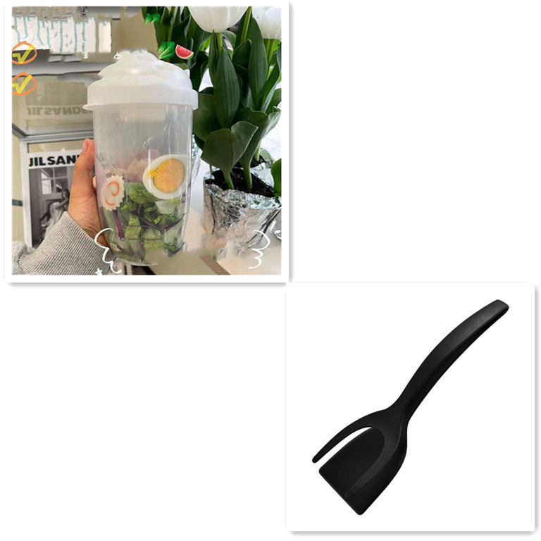 Hand holding a clear plastic salad cup filled with greens and sliced egg, with a white lid and matching black spork below.