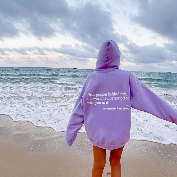 Person wearing an oversized lavender hoodie with white letter print for casual beach wear.