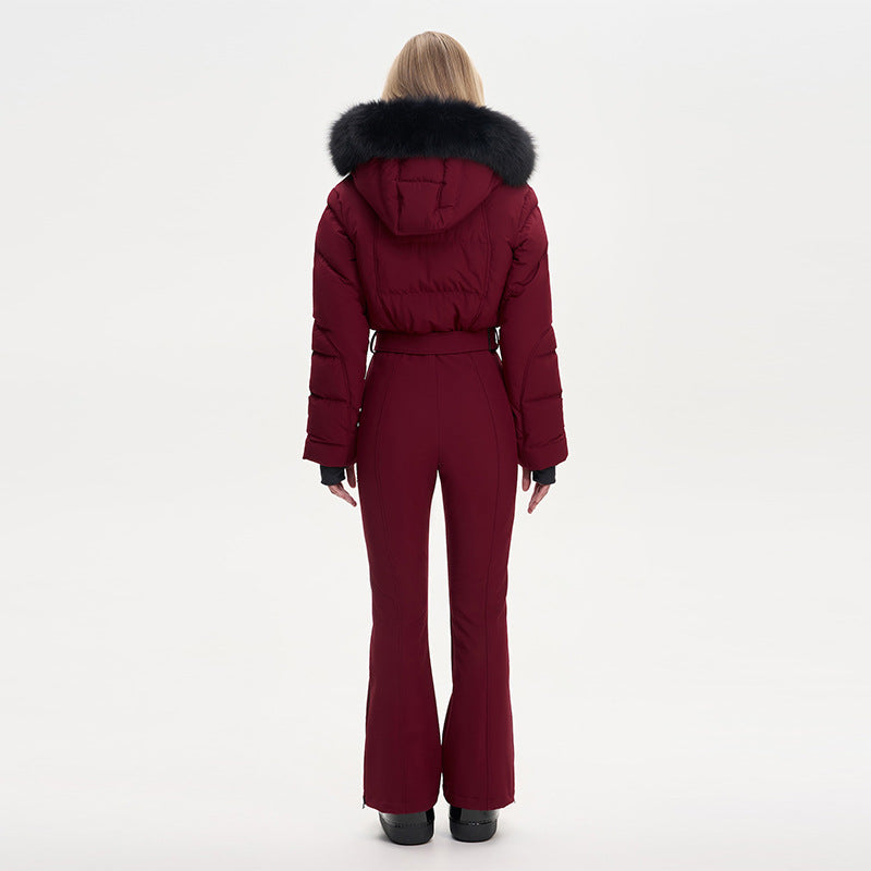 Rear view of a person wearing a maroon one-piece ski suit with a fur-trimmed hood and waist belt