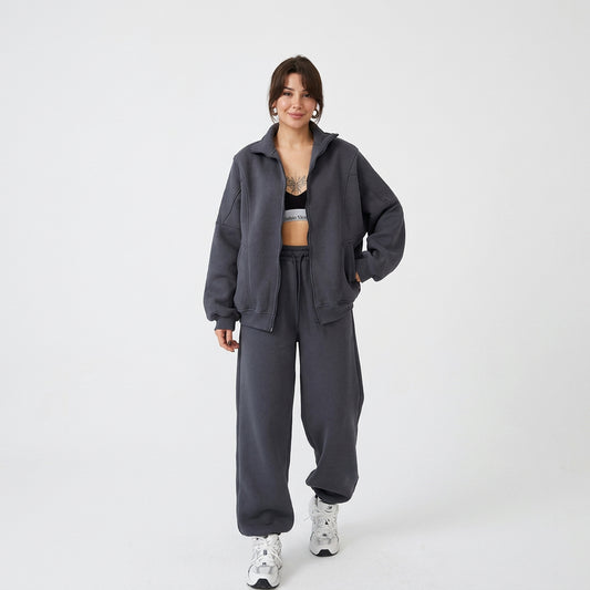 Woman wearing a dark grey oversized zip-up tracksuit and matching joggers, front view.