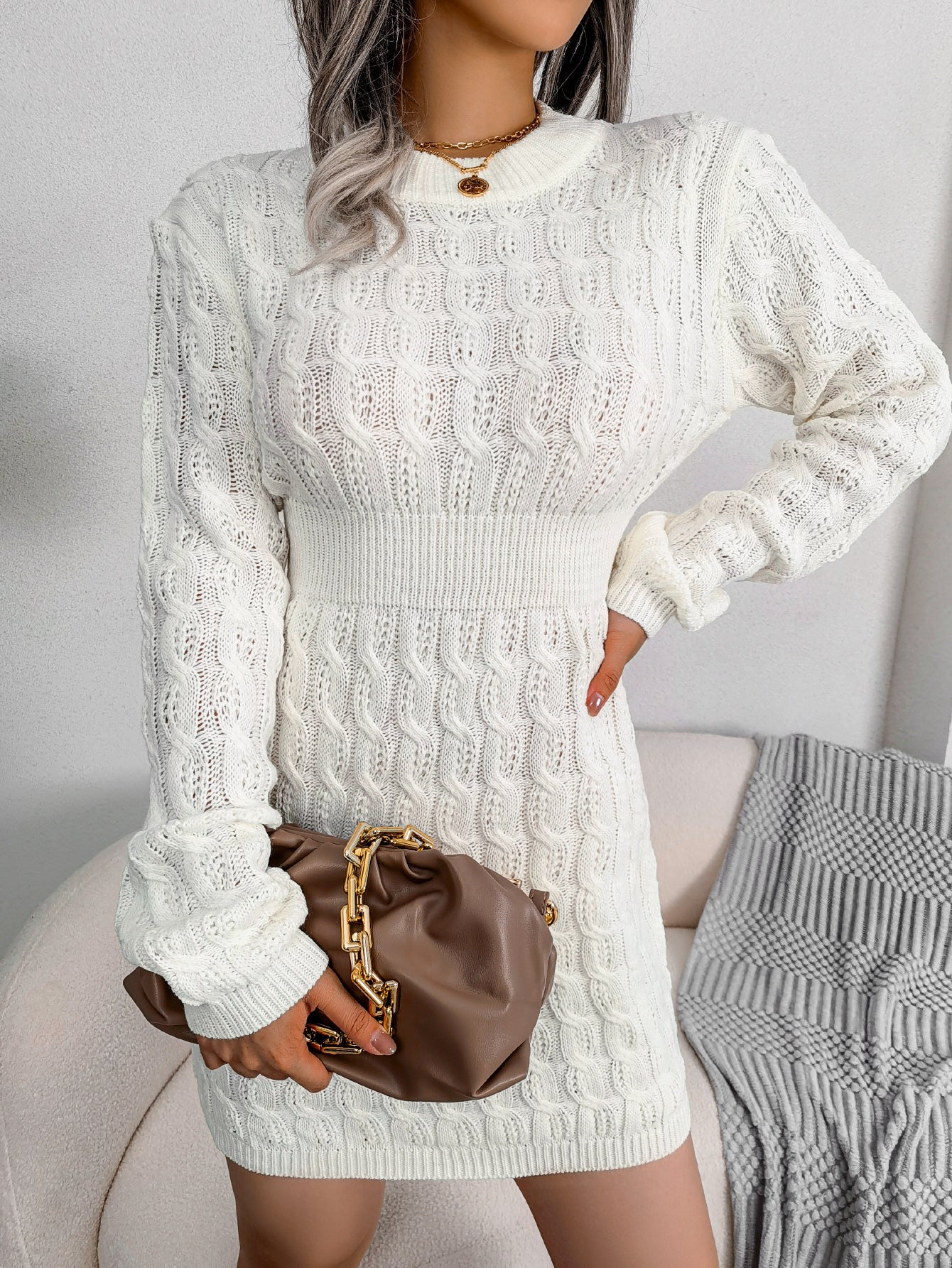 Cream white cable knit sweater dress with a fitted waist, worn for cold weather outings.