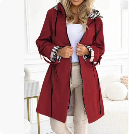 Woman wearing a red hooded coat with black drawstrings and plaid lining on the cuffs and hood.