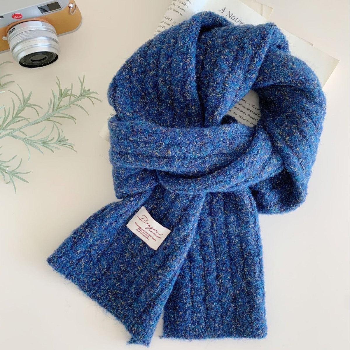 Blue textured knit scarf with a small white tag on one end.