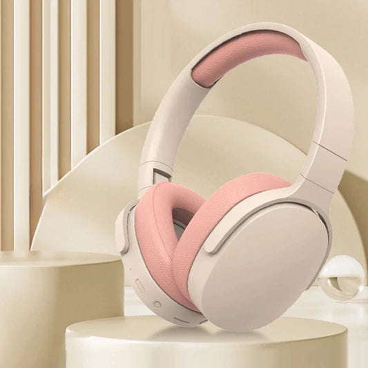 Beige and pink over-ear wireless headphones displayed on a neutral abstract pedestal background