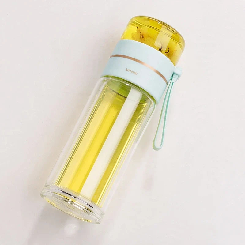 Double wall glass tea infuser bottle with light blue lid and carrying strap containing yellow tea on white background.