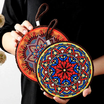 Two round mandala pot trivets with colorful geometric patterns and hanging rope loops.