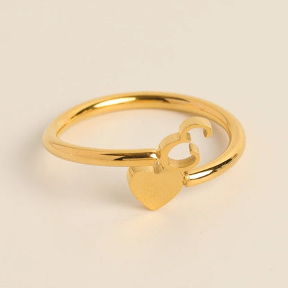 Gold adjustable ring featuring a dangling heart charm and initial letter E.