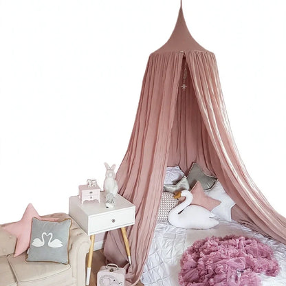 Dusty pink bed canopy draped over a child bed with swan pillows and tutu blanket.