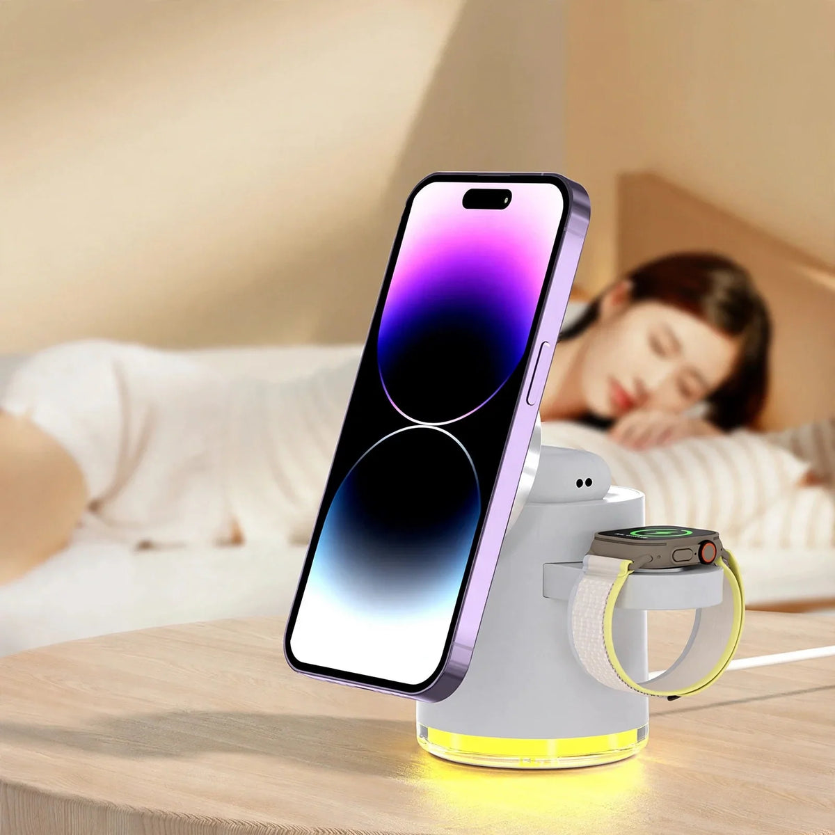 Magnetic wireless charging dock holding a smartphone, smartwatch, and earbuds with a glowing yellow base on a wooden table