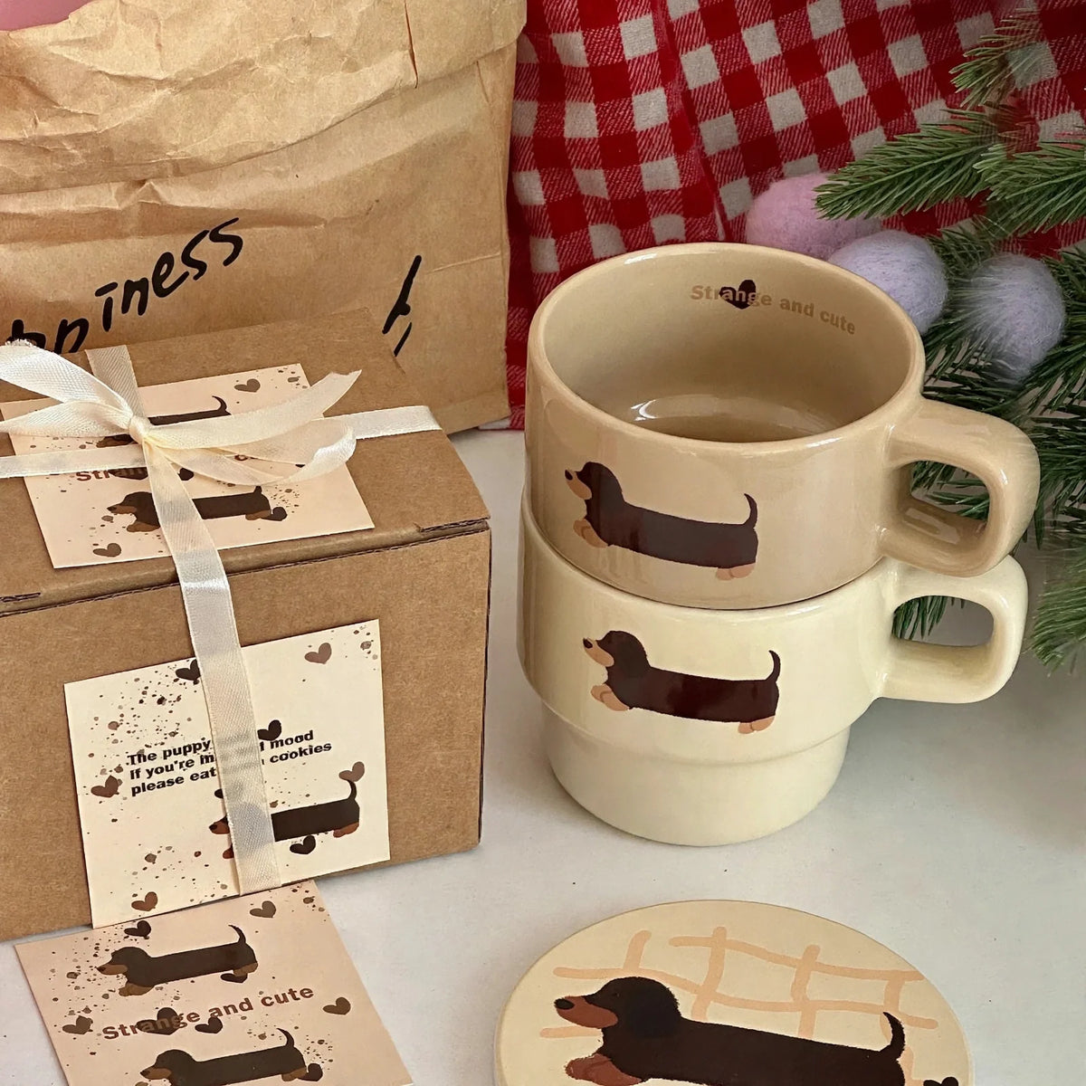 Two stacked ceramic mugs with dachshund illustrations, gift box, and matching coaster.
