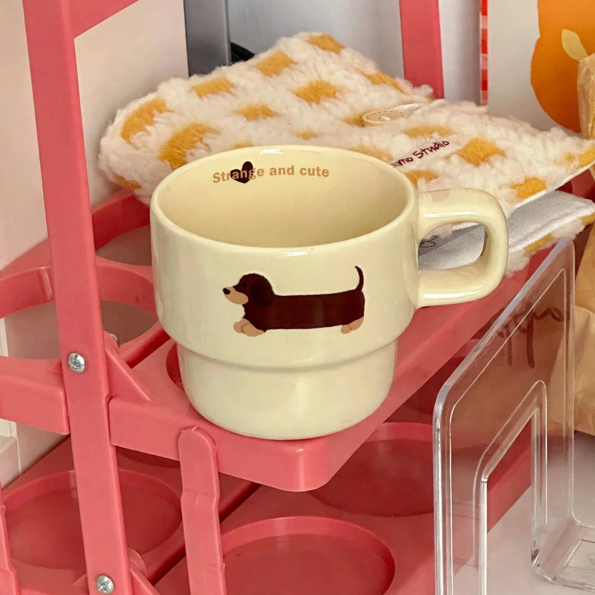 Cream ceramic coffee mug with brown dachshund graphic and interior text on a pink shelf