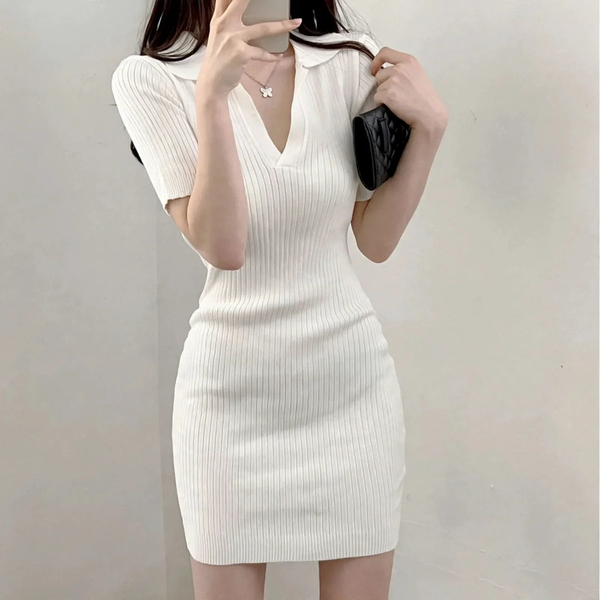 Woman wearing a short-sleeve white ribbed knit polo mini dress with a V-neckline.