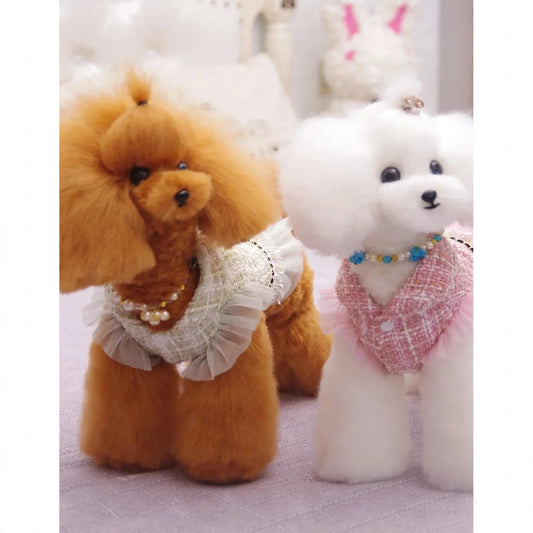 Two stuffed toy poodles wearing tweed dresses with ruffles and pearl necklaces