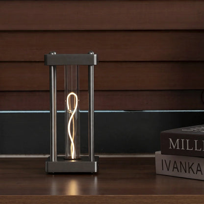 Square metal frame table lamp with a glowing filament tube and a balancing sphere inside.