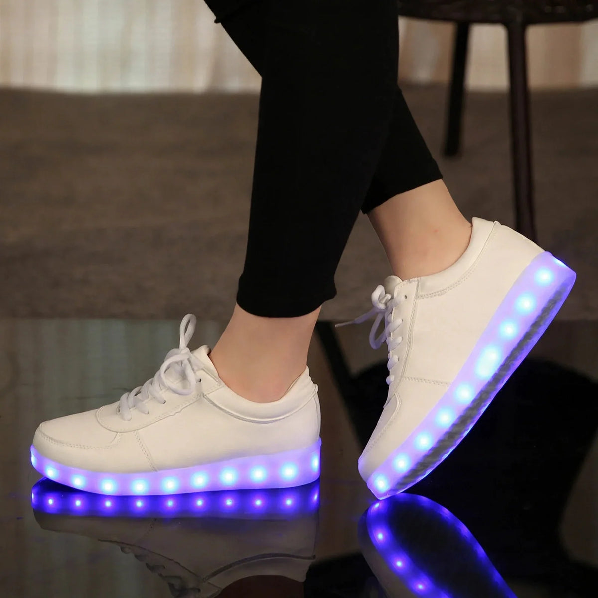 White lace-up sneakers with glowing purple LED light-up soles worn with black leggings.