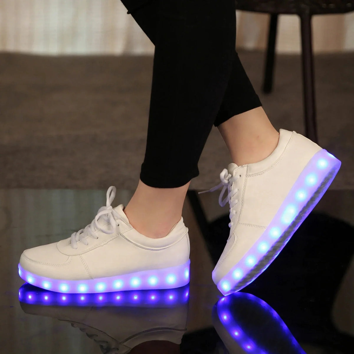 White lace-up sneakers with glowing purple LED light-up soles worn with black leggings.