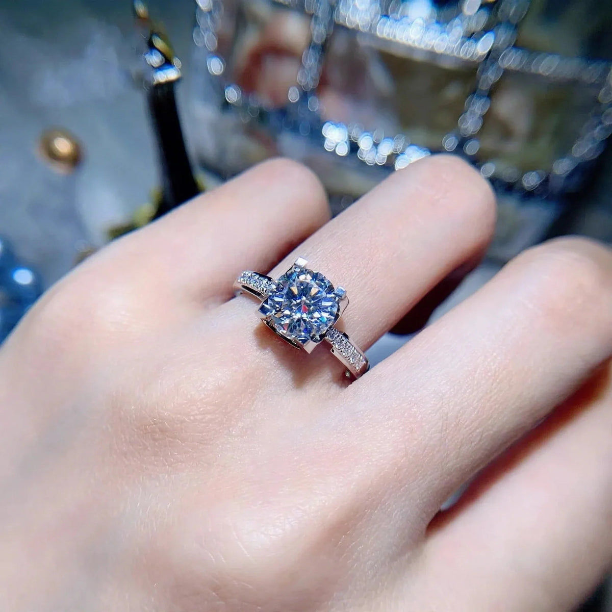 Round solitaire ring with a large center stone and pavé band worn on a finger