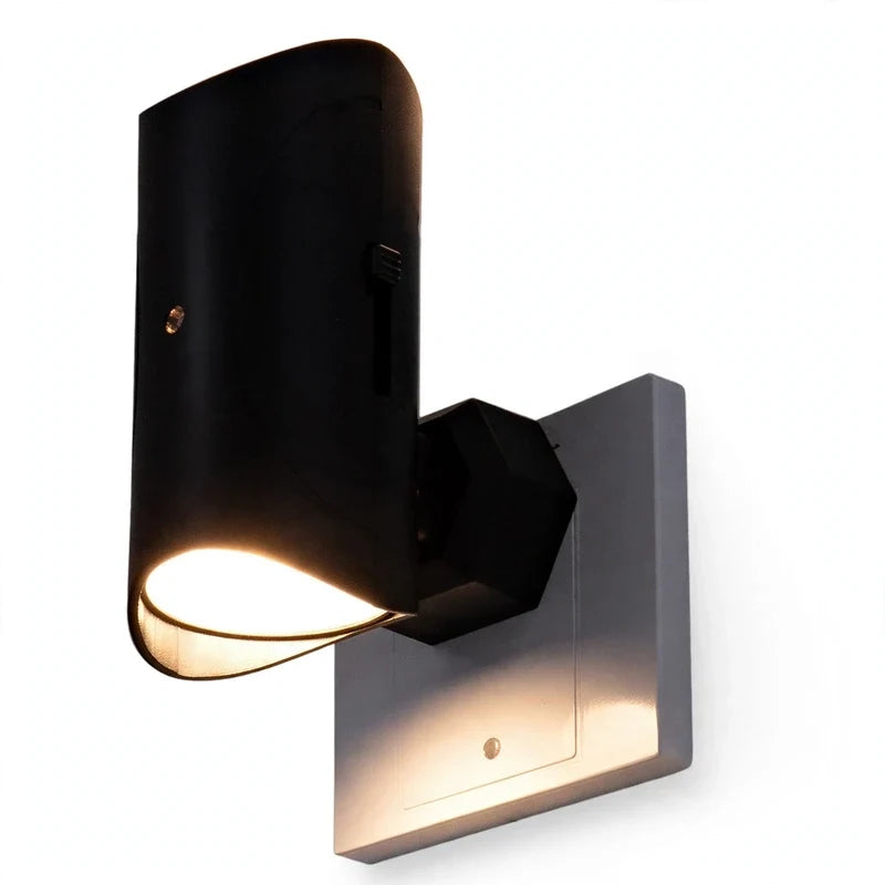 Black motion sensor plug-in LED night light glowing on a white wall.
