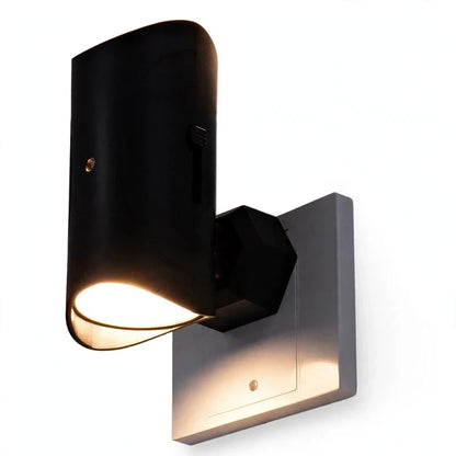 Black motion sensor plug-in LED night light glowing on a white wall.