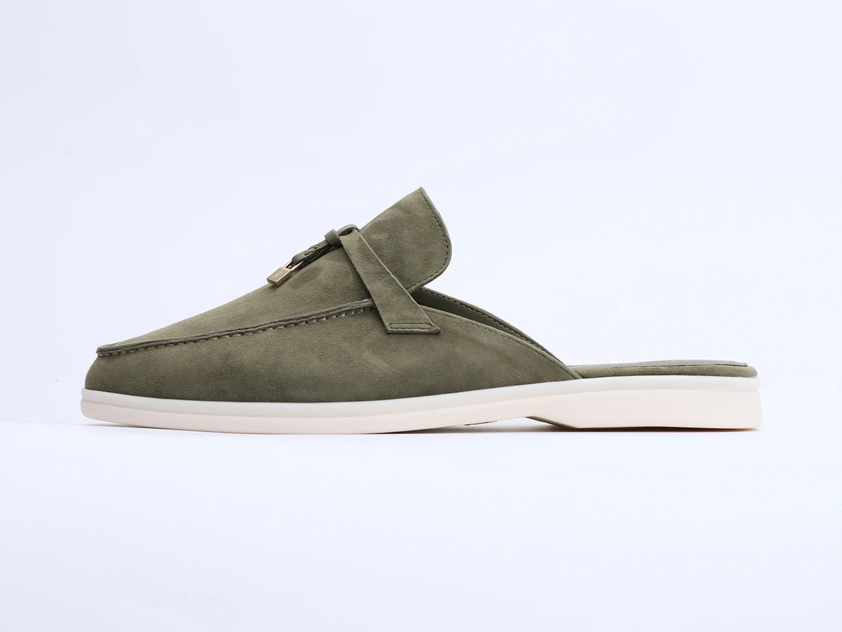 Olive green suede mule with a flat white sole and tassel detail on the upper, side view.