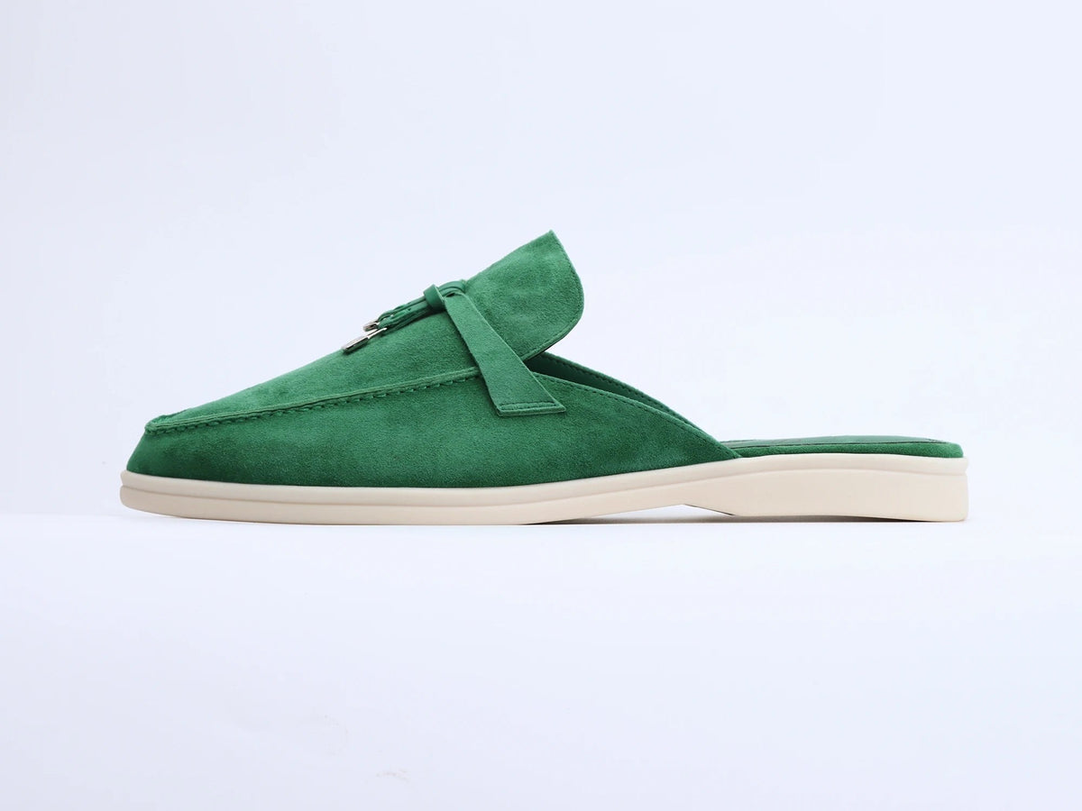 Side view of green suede mule with tassel, metal ring detail, and flat cream sole