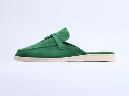 Side view of green suede mule with tassel, metal ring detail, and flat cream sole