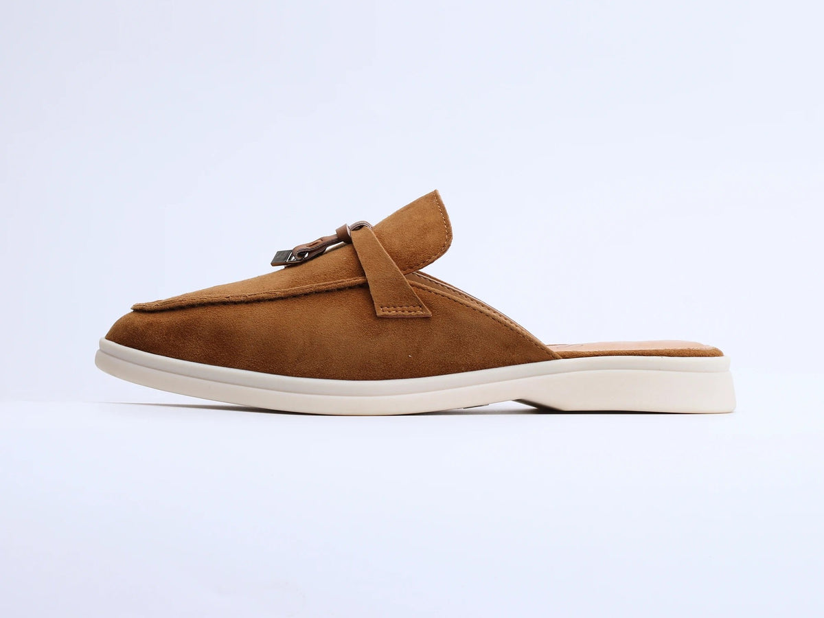 Brown suede mule with a tassel and metal ring on a white sole, side view
