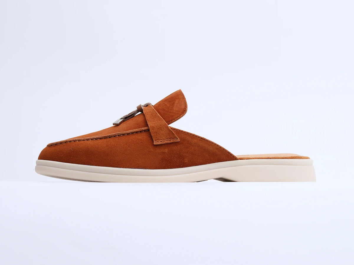 Brown suede mule with a tassel and metal ring on a white background, side view.