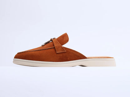 Brown suede mule with a tassel and metal ring on a white background, side view.