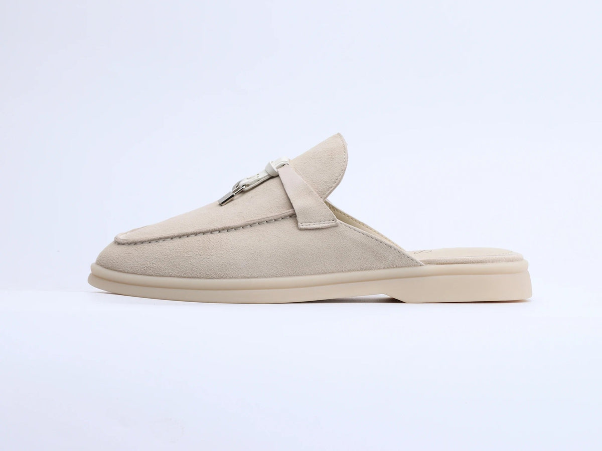 Beige suede mule with a metal ring and tassel detail, shown in profile.