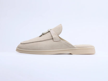 Beige suede mule with a metal ring and tassel detail, shown in profile.