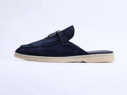 Navy blue suede mule with side strap and tassel detail on a light sole, side profile