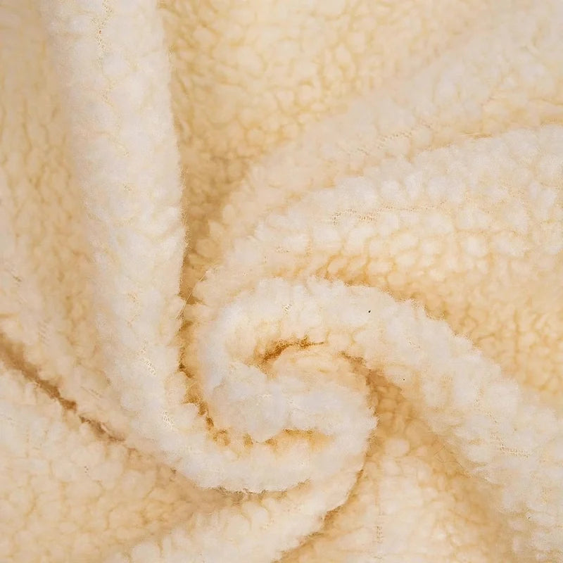 Close-up of soft beige sherpa fleece fabric texture.