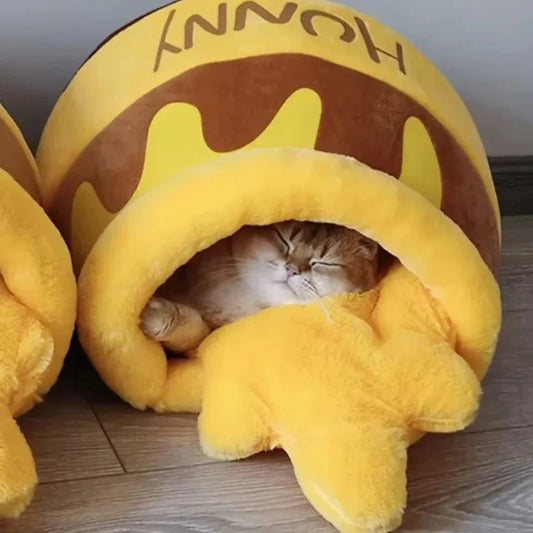 Orange cat sleeping inside a plush yellow and brown honey pot pet cave bed.