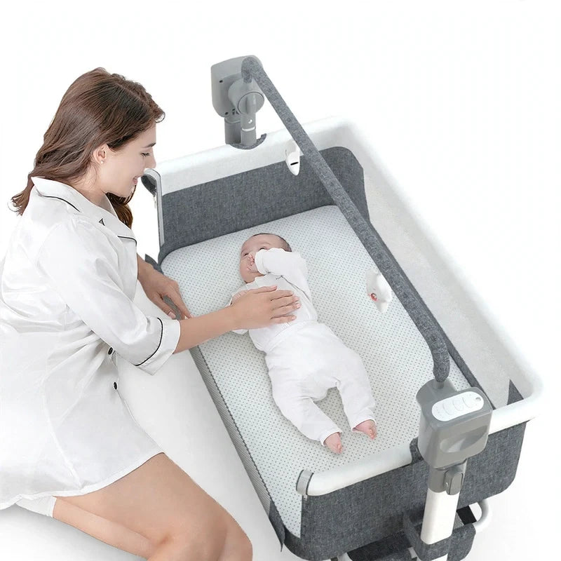 Woman kneeling beside a motorized baby bassinet with a baby lying inside