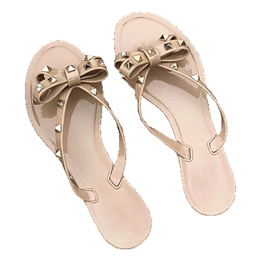 Beige jelly sandals with gold studded bows, slip-on shoes for casual wear.