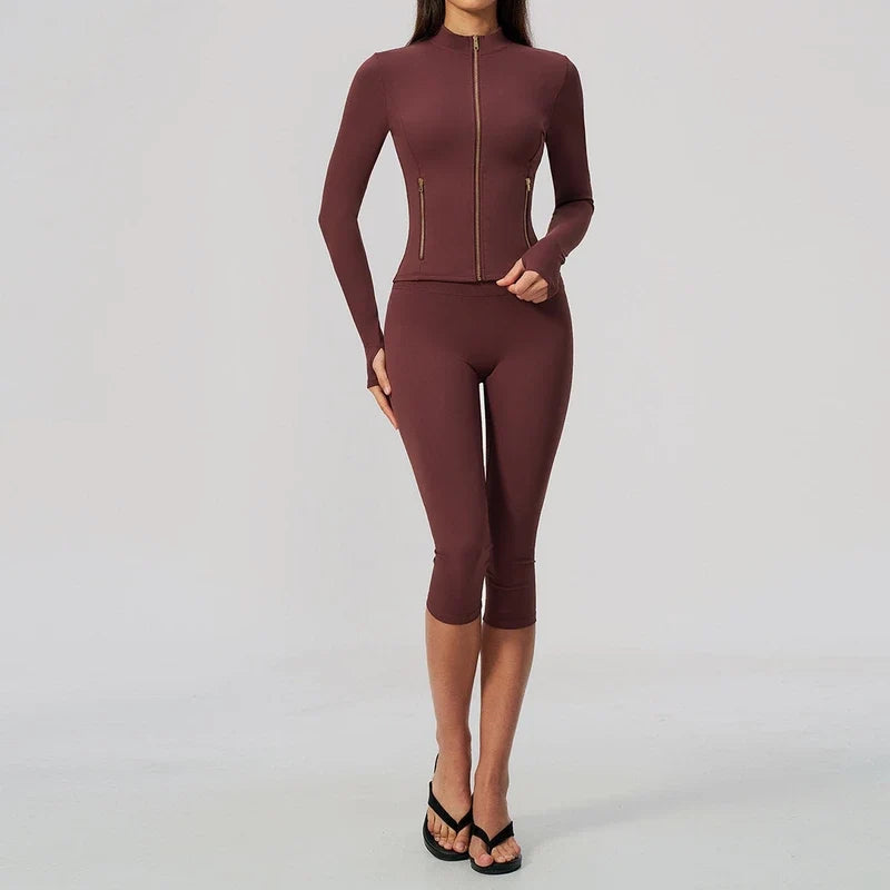 Maroon athletic full-zip jacket with long sleeves and matching cropped leggings worn by a model.