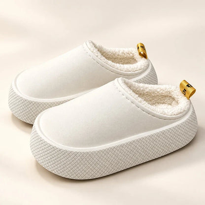 White fleece-lined slip-on slippers with thick textured platform soles and small yellow heel pull tabs.