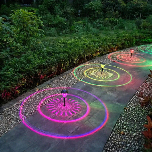 Solar garden path lights casting colorful circular ripple patterns on a paved walkway at night.