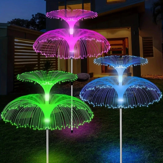 Three multi-tiered solar jellyfish garden light stakes glowing in pink, green, and blue on a lawn.