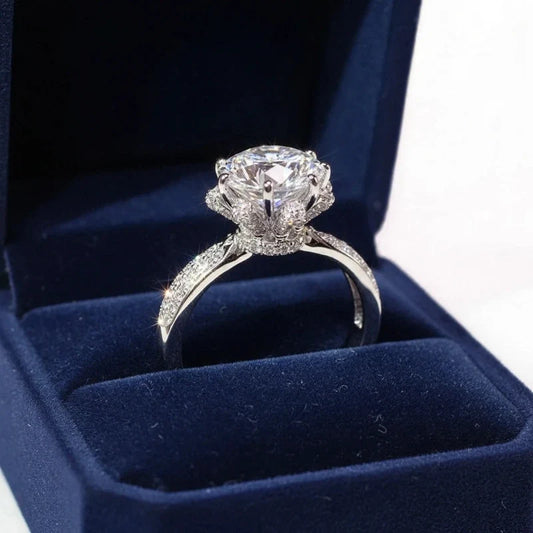 Round solitaire ring with pave band inside a dark blue velvet ring box