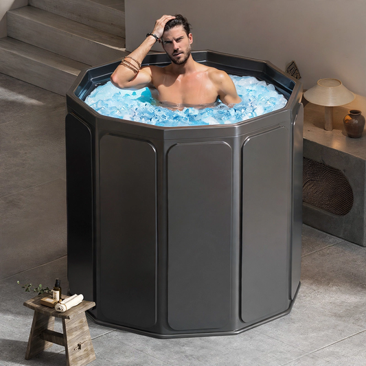 Man sitting in a dark gray octagonal portable ice bath tub filled with water and ice cubes.