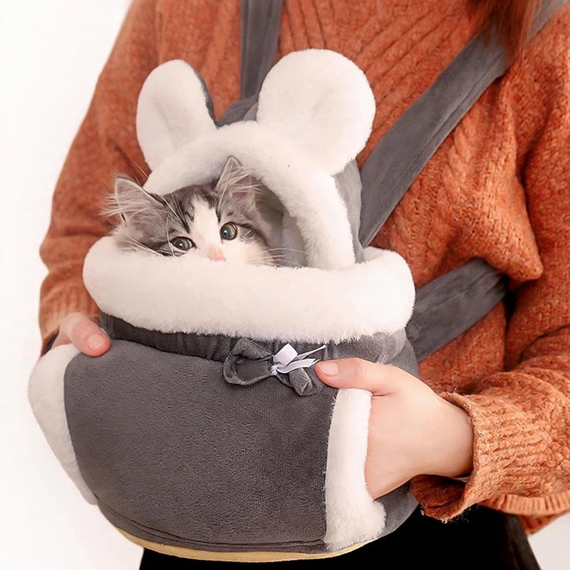 Fluffy grey pet carrier backpack with white trim holding a kitten, worn on the front.