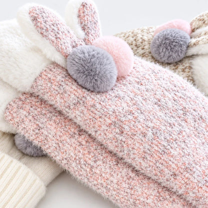Pink and white knit mittens featuring plush bunny ears and gray and pink pom poms.