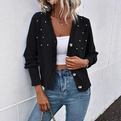 Black V-neck knit cardigan with faux pearl bead accents and front buttons worn with blue jeans.