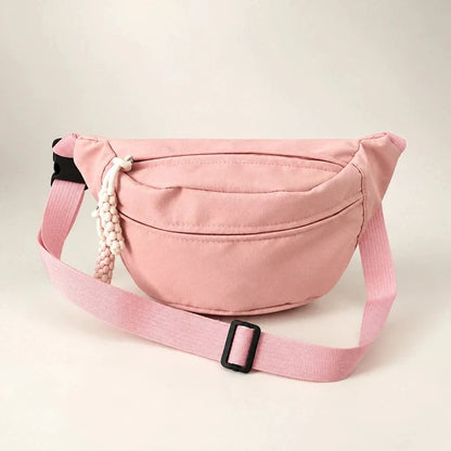 Pink crescent sling bag with an adjustable strap, black buckle, and beaded zipper pull.