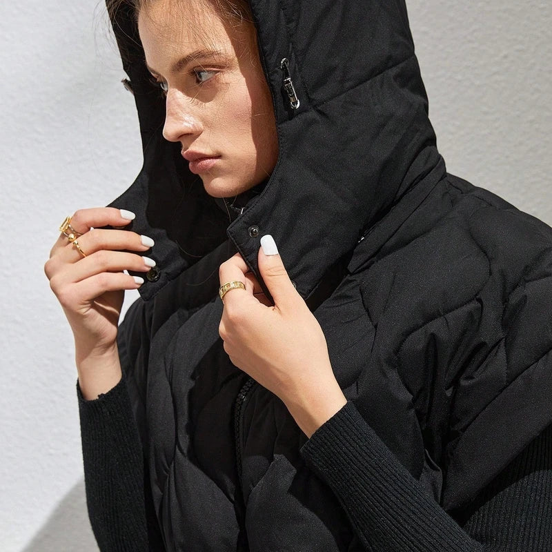 Woman wearing a black quilted puffer vest with hood and black long-sleeve underlayer.