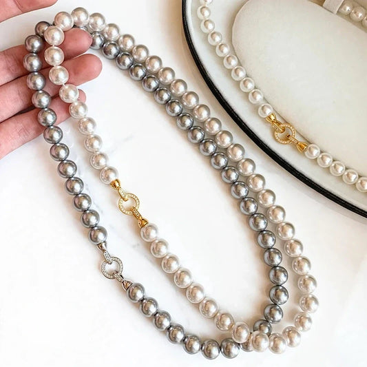 Two-strand pearl necklace with one white and one grey strand, featuring gold-toned clasps with round stone accents.